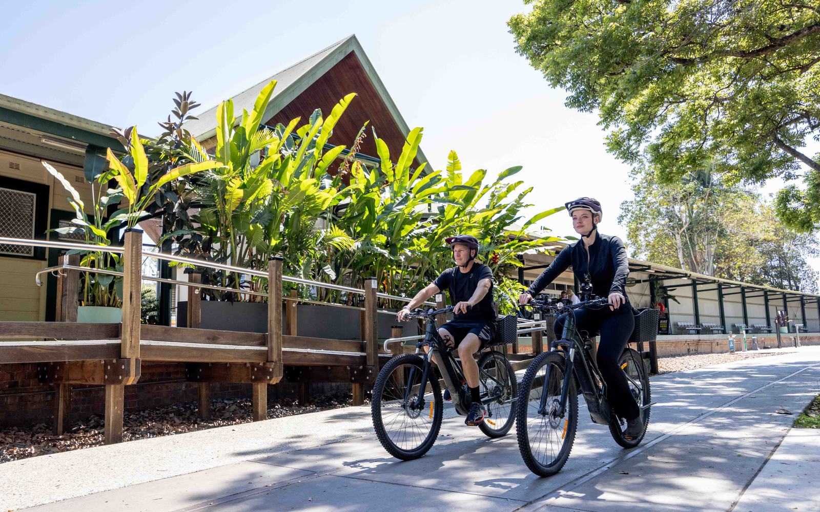 Two riders on the Northern Rivers Rail Trail passing a heritage station building